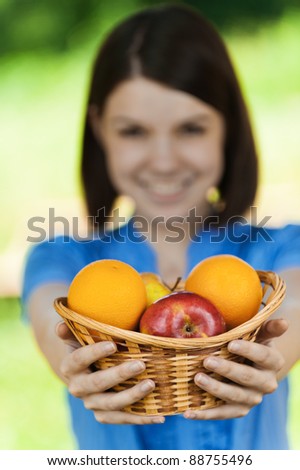 beautiful young girl reaches out ahead basket fruit blurred background