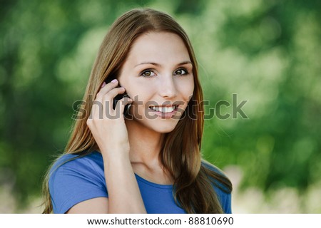 pretty young woman long hair smiling talking phone background summer green park