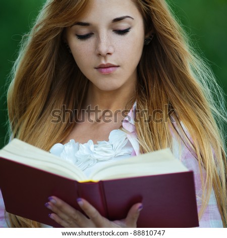young serious woman park holding reading red book