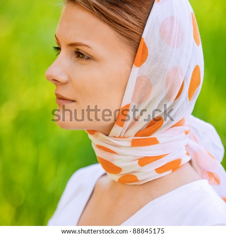 portrait of young beautiful woman wearing shawl and white blouse, standing at summer green park