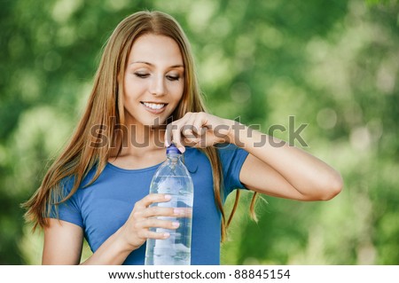 attractive young woman long hair smiling opens bottle wate background summer green forest