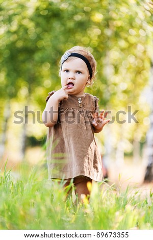 portrait little cute girl dress walking meadow green grass holding finger mouth background summer green park