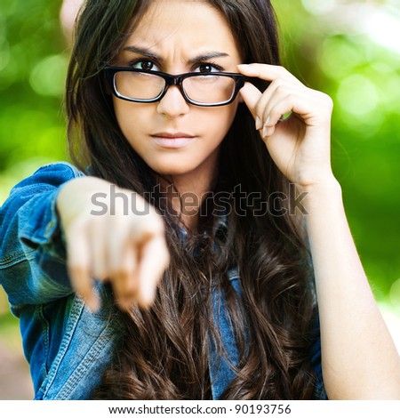 beautiful young woman long dark hair wearing glasses severe frown points finger forward - stock-photo-beautiful-young-woman-long-dark-hair-wearing-glasses-severe-frown-points-finger-forward-90193756