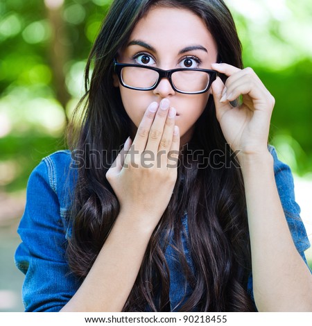 beautiful young long-haired woman glasses surprised covers mouth