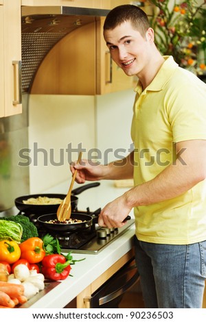 portrait of a slender man standing in kitchen preparing to eat in a griddle