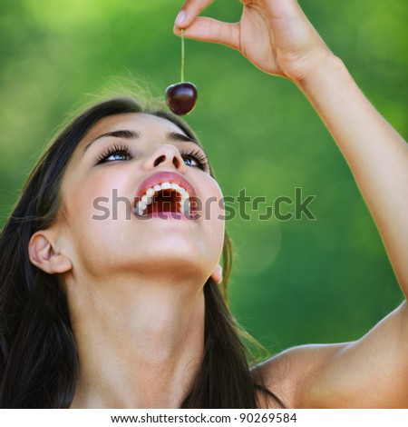 attractive young woman bare shoulders holding cherry open mouth background summer green forest