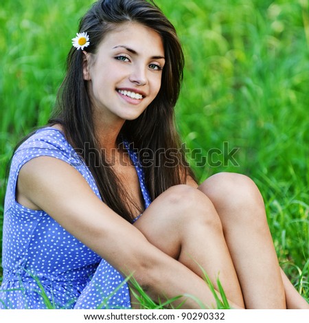charming young dark-haired woman sitting green grass flower ear smiling background green meadow