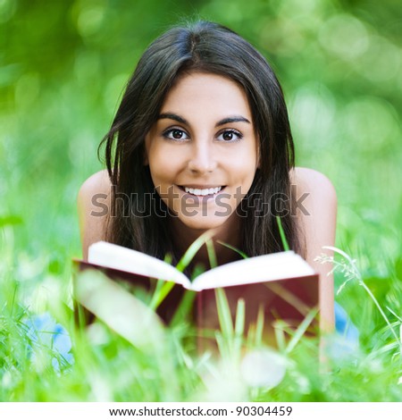 young girl lying grass summer reading red book