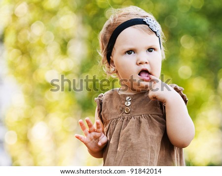 portrait little cute girl dress walking holding finger mouth background summer green park