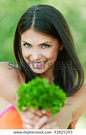 portrait of beautiful young dark-haired sexy girl seductively baring her shoulders with bundle of herbs (dill) in hands