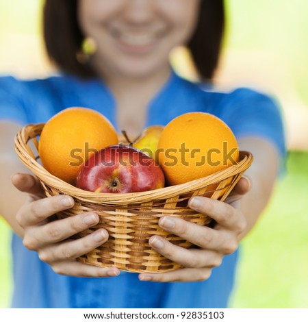beautiful young girl reaches out ahead basket fruit blurred background