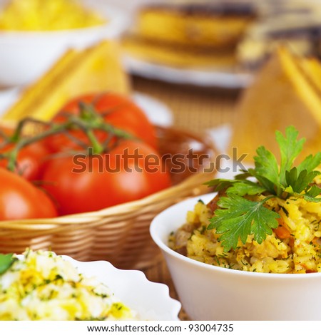closeup delicious prepared pilaf, salad, cake decorated chocolate, twig red tomatoes wicker basket background wooden table