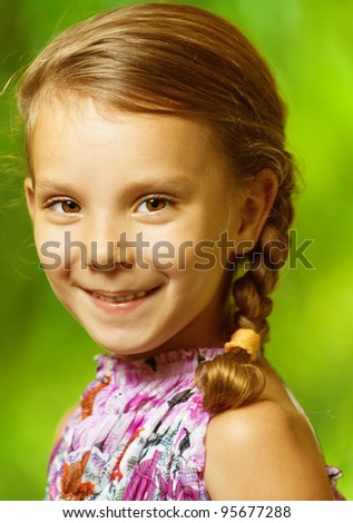 portrait of beautiful smiling girl with pigtail to green park background