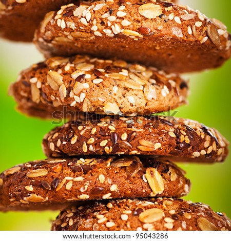 delicious oatmeal cookies with splash of sunflower seeds, sesame seeds on wooden table laid out in row on green background