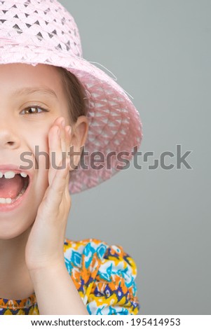 Half face of beautiful young girl shouts loud voice, on gray background.
