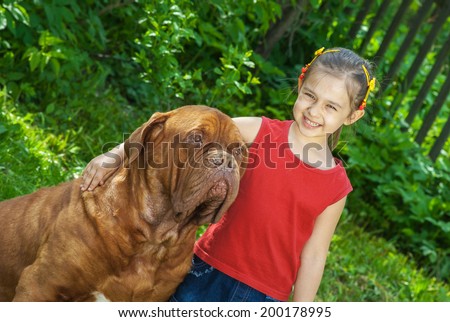 Young smiling girl astride big dog of breed FRENCH MASTIFF, DOGUE DE BORDEAUX