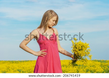 Beautiful sad young woman in red dress with bouquet in her hands on spring field with yellow flowers.