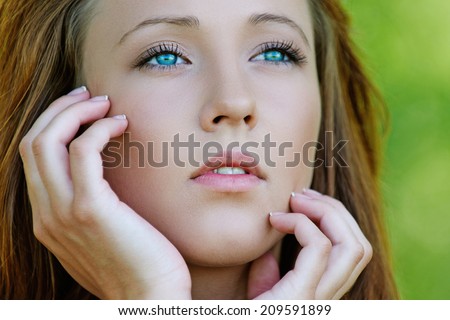 Portrait of pretty dark-haired pensive girl at summer green park.