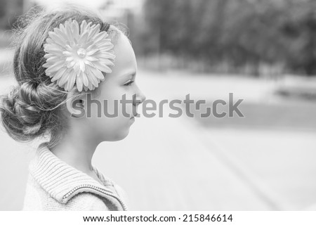 Portrait of beautiful smiling little girl in profile, against background of summer city park.