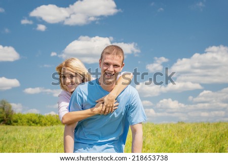 Young woman hugging man against background of green summer meadows.