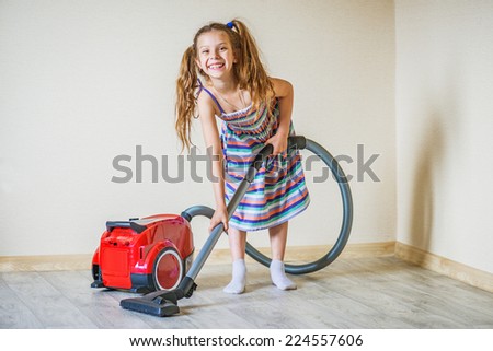 Little beautiful smiling girl running with vacuum cleaner at home.
