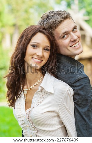 Young beautiful man holds beloved on back and laughs.