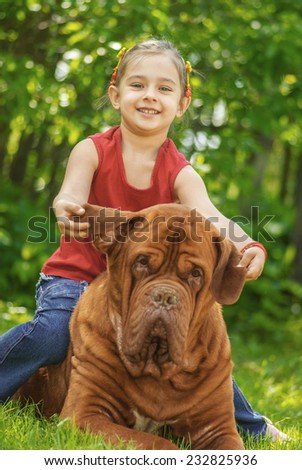 Young smiling girl astride big dog of breed FRENCH MASTIFF, DOGUE DE BORDEAUX