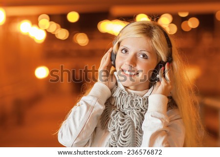 Beautiful woman in night tunnel listens to music through headphones.