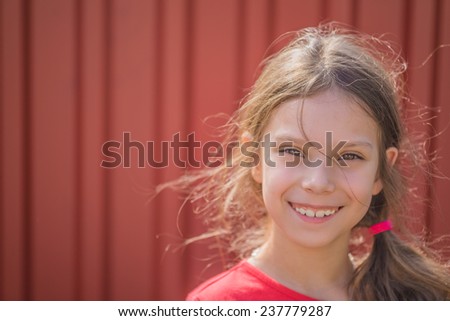 Portrait of beautiful smiling young girl on background of red metal fence.