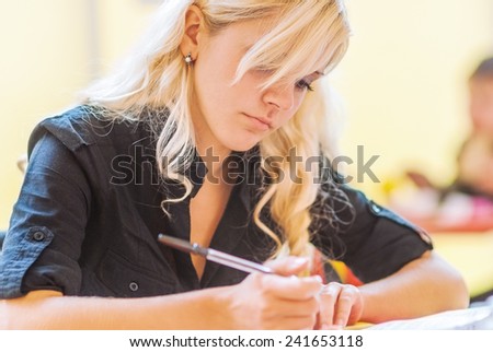 Young woman-student performs written work. Black and white photo.