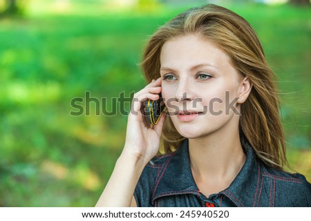 Young beautiful woman talks by mobile phone, on green background.