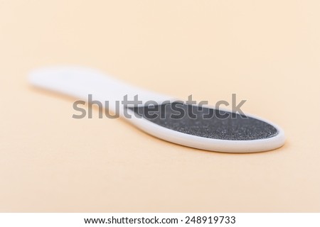 Pedicure tool for heels lying on gray napkin.