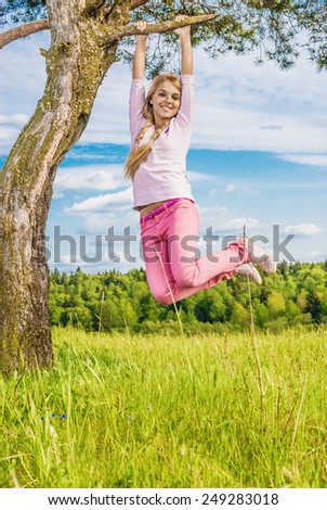 young beautiful woman laughs plays nature, being turned round tree