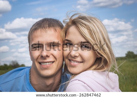 Young beautiful woman and young beautiful man embrace against dark blue sky clouds.