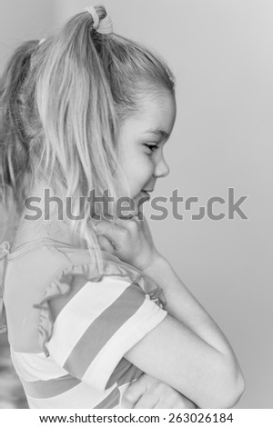 Portrait of beautiful smiling little girl in profile. Black-and-white photo.