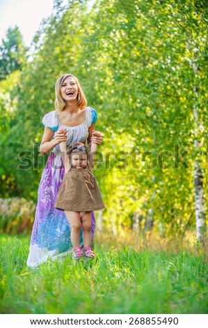 beautiful young woman long dress plays child field background summer meadow green trees