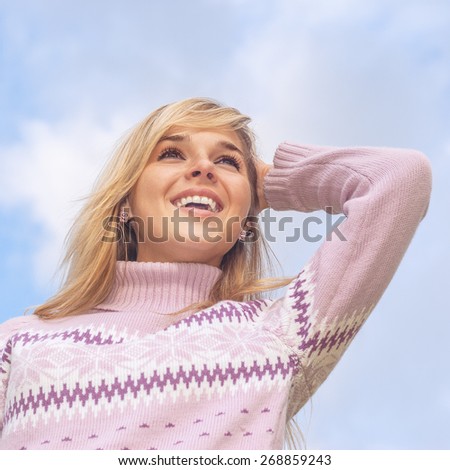 The young beautiful woman has a rest, having combined hands behind head, and smiles, against dark blue sky.