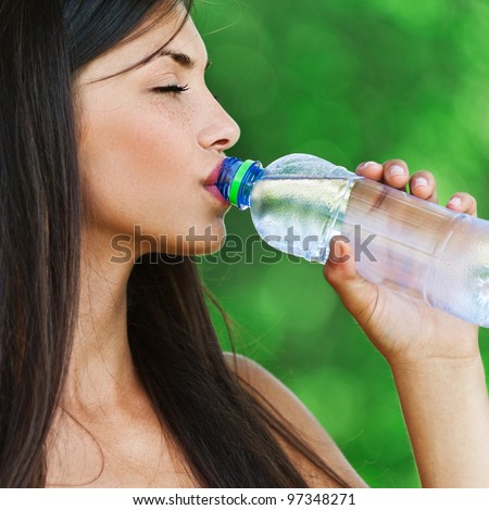 portrait pretty young woman background green summer park drinking water bottle