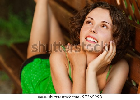 outside portrait of young beautiful happy woman laying on bench in park