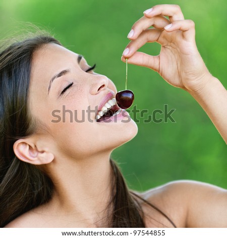 attractive young woman bare shoulders holding cherry open mouth background summer green forest