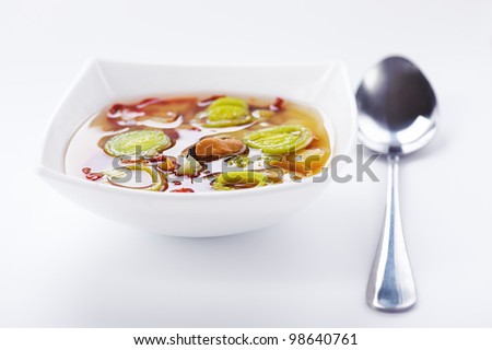Onion soup and spoon on white table.