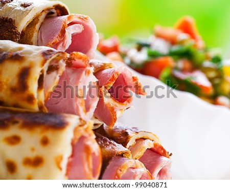 on green background, meat rolls (bacon, ham, ham) in the omelet, vegetable salad (cucumbers, tomatoes, parsley)