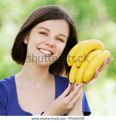 Portrait of young beautiful attractive smiling woman holding bananas at summer green park
