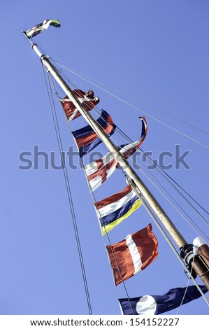 Seen from below a selection of colourful ships flags up a mast and fluttering in the wind