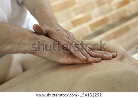 A pair of female Osteopaths hands giving treatment and massage to the back of another female