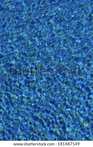 the rippled surface of blue swimming pool water with tiled base
