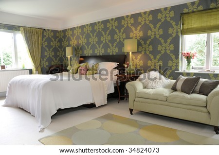 Luxury interior designed bedroom with large bed and chaise lounge