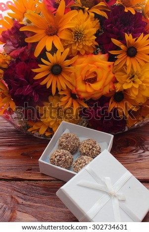 on a wooden board are a bunch of flowers and a box of chocolates
