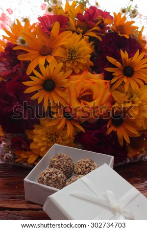 bouquet of flowers with candy lie on a wooden board