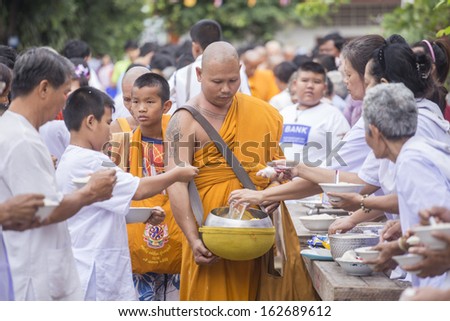 Nakhon Ratchasima, THAILAND - OCT 20:Give alms to a Buddhist monk Buddhist Monks for alms in The Tak Bat  Ceremony at Phrabuddhabat Temple on October 20, 2013 in Nakhon Ratchasima, Thailand